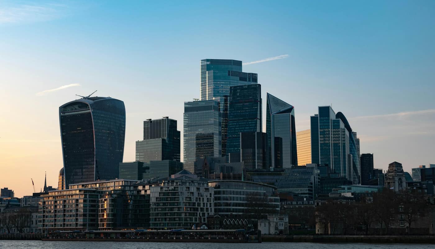 City of London skyscrapers rising above riverside buildings at dusk