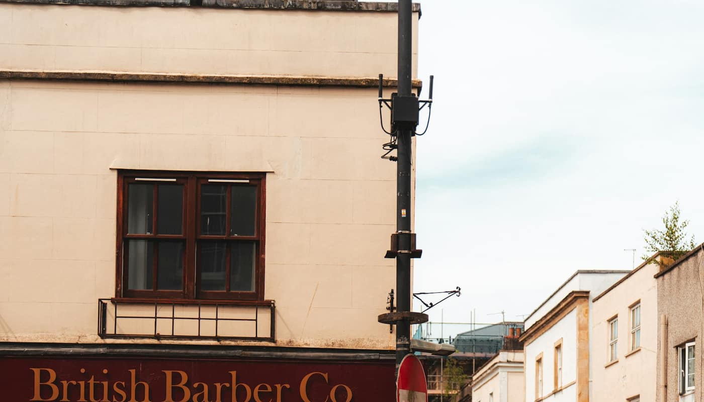 An independent shop front with a red fascia reading British Barber Co on a quiet street