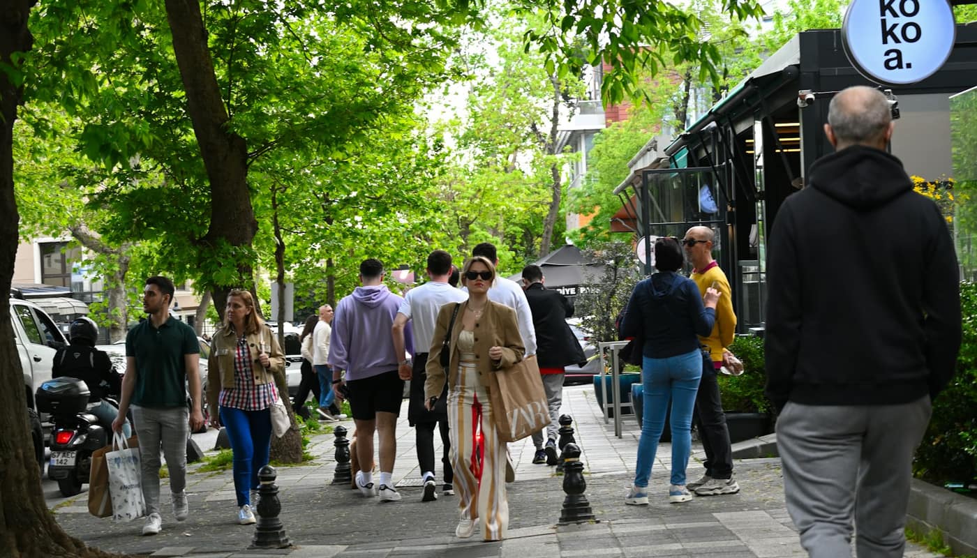 People walking along a tree-lined pedestrian street