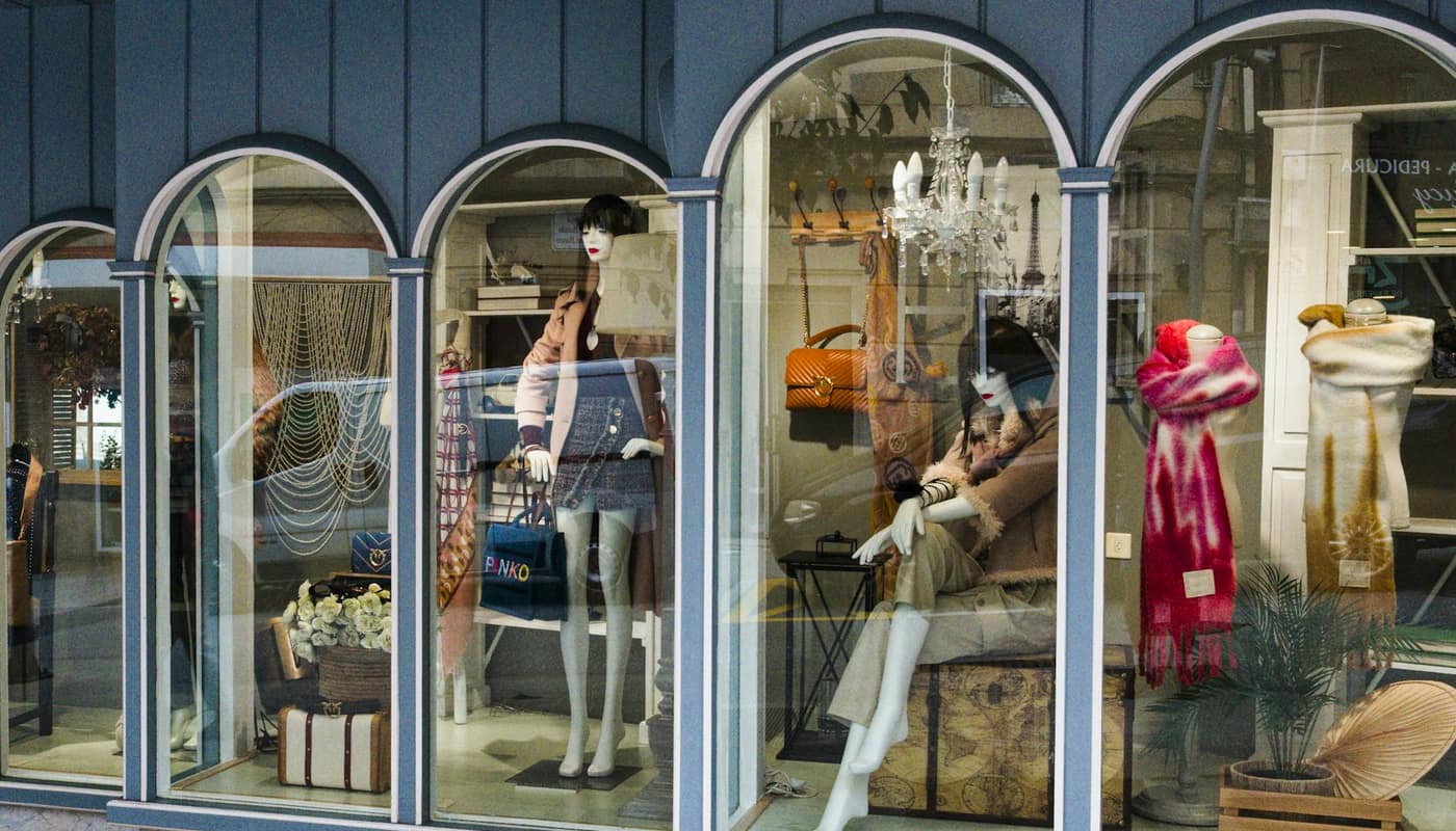 Mannequins in an arched shop window dressed in coats and scarves