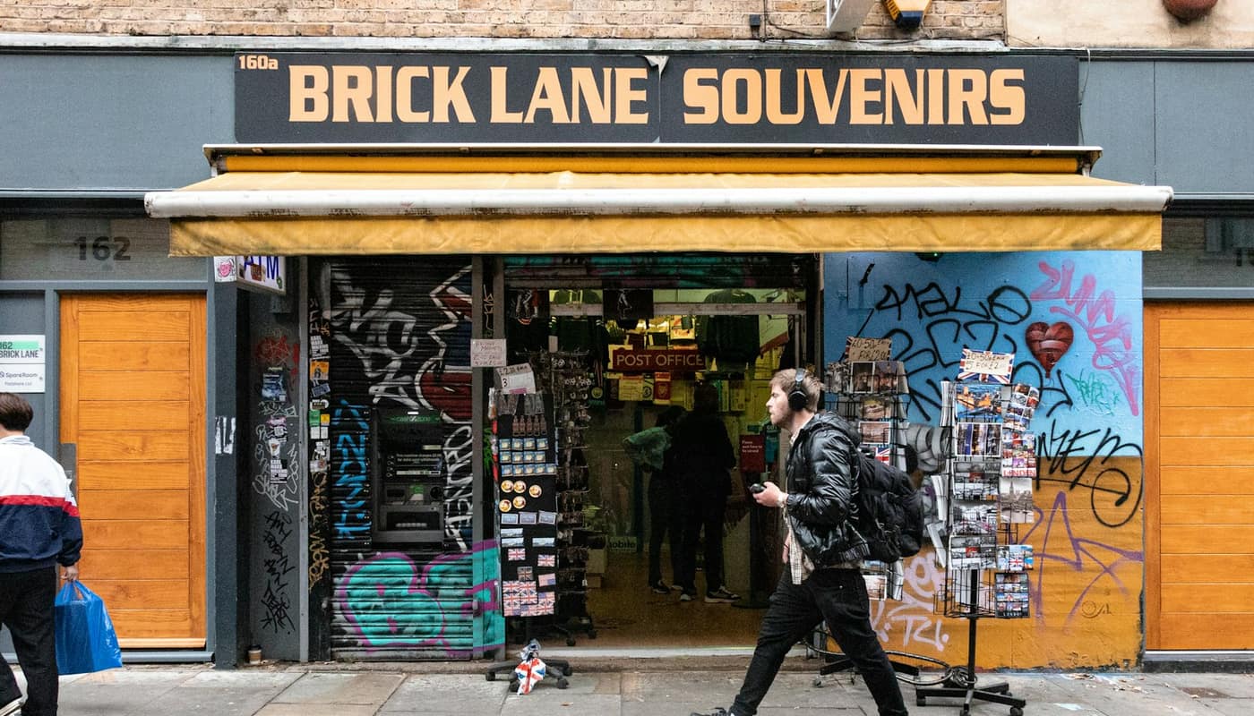 A pedestrian walking past the Brick Lane Souvenirs shop front