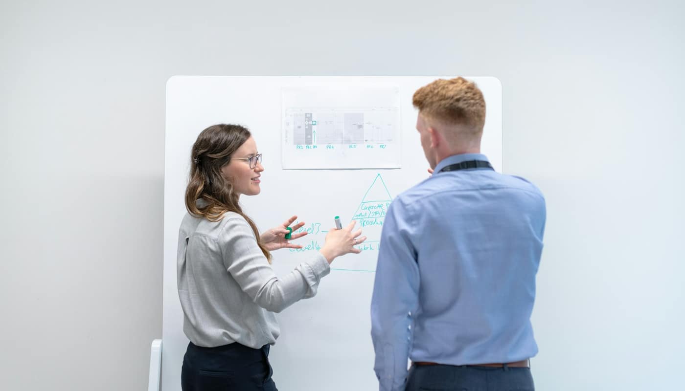 Two colleagues discussing ideas at a whiteboard