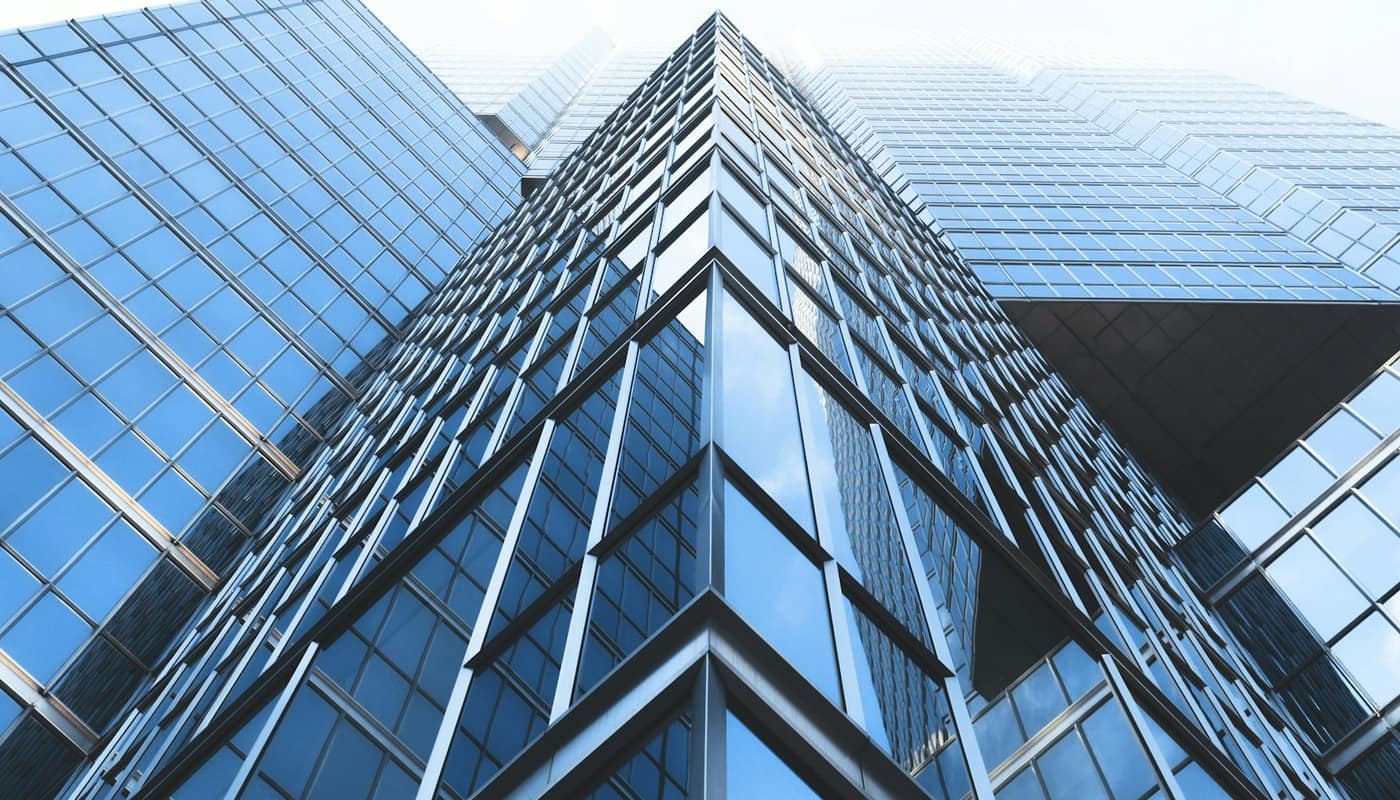 Looking up at the glass facade of a tall office building